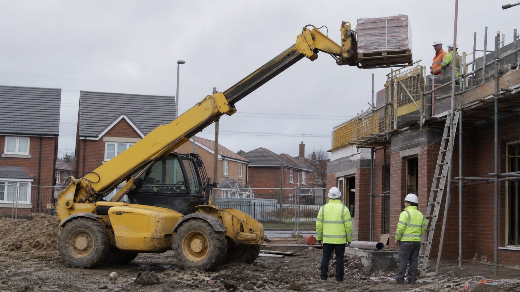 Telehandler lifting a pallet of building materials to scaffolding on a UK house-building site